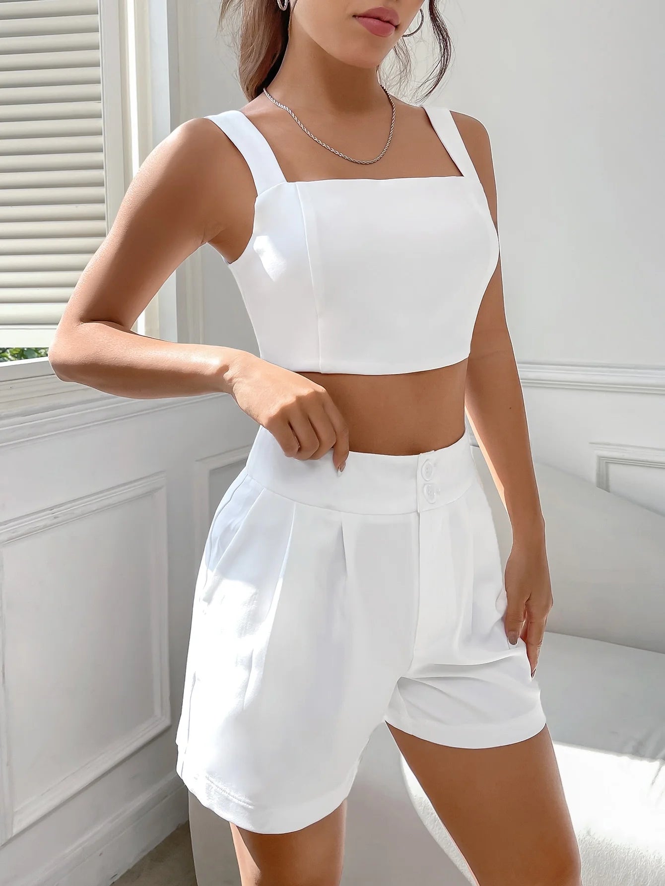 A casual suit for women with a one-neck halter top and white shorts